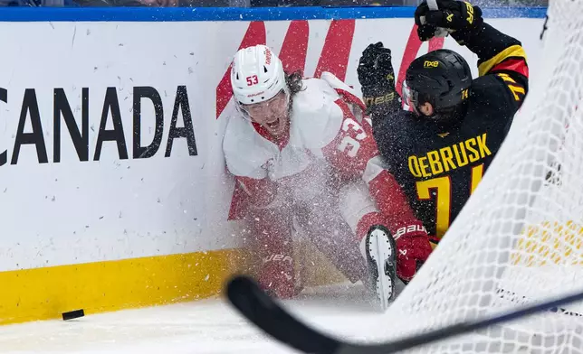 Detroit Red Wings' Moritz Seider (53) and Vancouver Canucks' Jake DeBrusk (74) collide during the third period of an NHL hockey game in Vancouver, British Columbia, Thursday, Oct. 22, 2026. (Ethan Cairns/The Canadian Press via AP)