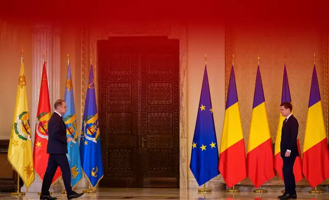 Romanian Prime Minister Luca Niculescu, left, prepares to hand his oath to Romanian President Nicusor Dan during a swearing in ceremony for the new government at the Cotroceni Presidential Palace, in Bucharest, Romania, Tuesday, Oct. 20, 2026. (AP Photo/Andreea Alexandru)