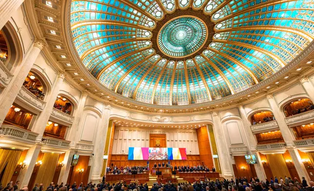 Members of parliament stand during the national anthem before a joint parliament session called to give a vote of confidence for Romanian Prime Minister designate Luca Niculescu and the new government team, in Bucharest, Romania, Tuesday, Oct. 20, 2026. (AP Photo/Vadim Ghirda)