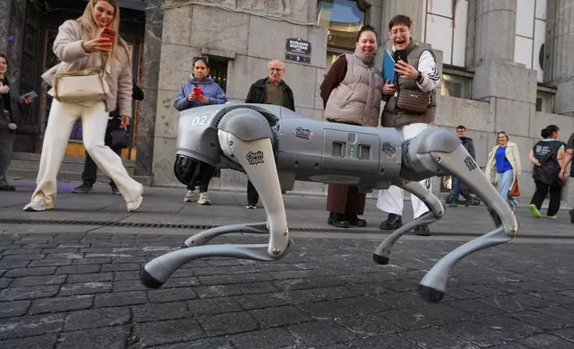 People look at an animal shaped robot promoting a nearby entertainment museum in St. Petersburg, Russia, Thursday, Oct. 1, 2026. (AP Photo/Dmitri Lovetsky)