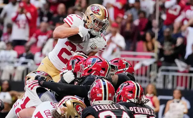San Francisco 49ers running back Christian McCaffrey, top, leaps into the end zone over Atlanta Falcons' A.J. Terrell Jr. (24), Jared Ivey (51) and other defenders to score a touchdown during the first half of an NFL football game in Atlanta, Sunday, Oct. 25, 2026. (AP Photo/Brynn Anderson)