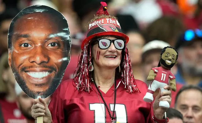 An Arizona Cardinals fan holds a Larry Fitzgerald head and doll during the first half of an NFL football game against the Denver Broncos in Glendale, Ariz., Sunday, Oct. 25, 2026. Fitzgerald will be inducted into the Ring of Honor and have his number retired at halftime. (AP Photo/Ross D. Franklin)