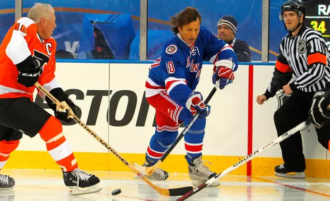 FILE -Ron Duguay, center, of the New York Rangers Alumni team passes the puck past Bob Clarke, of the Philadelphia Flyers Alumni team during the Winter Classic Alumni hockey game with the Philadelphia Flyers Alumni team, Saturday, Dec. 31, 2011 in Philadelphia. (AP Photo/Tom Mihalek, File)