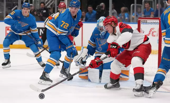 Carolina Hurricanes' Jackson Blake (53) reaches for a loose puck as St. Louis Blues' Justin Barron (72) defends during the third period of an NHL hockey game Saturday, Oct. 24, 2026, in St. Louis. (AP Photo/Jeff Roberson)