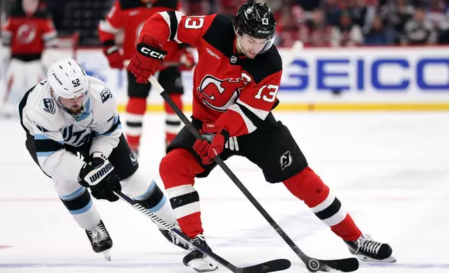 New Jersey Devils center Nico Hischier (13) battles for the puck with Utah Mammoth defenseman MacKenzie Weegar (52) during the second period of an NHL hockey game Tuesday, Oct. 6, 2026, in Newark, N.J. (AP Photo/Adam Hunger)