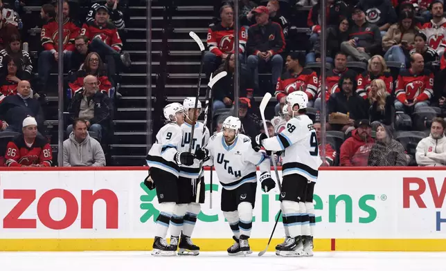 Utah Mammoth center Nick Schmaltz (8) is congratulated by teammates after scoring a goal during the second period of an NHL hockey game against the New Jersey Devils, Tuesday, Oct. 6, 2026, in Newark, N.J. (AP Photo/Adam Hunger)