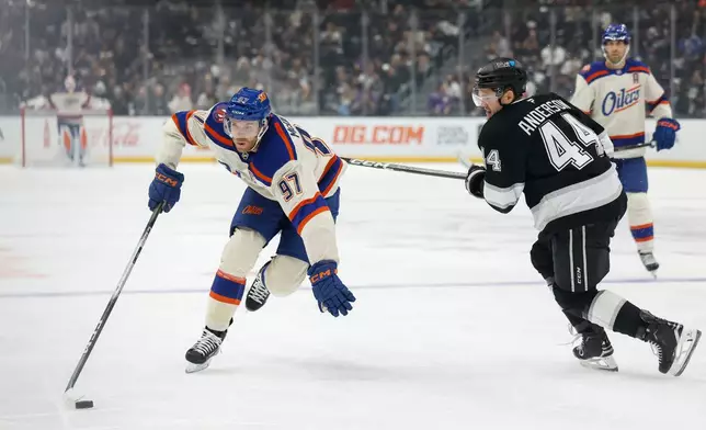 Edmonton Oilers center Connor McDavid (97), left, skates past Los Angeles Kings defenseman Mikey Anderson (44), right, with the puck during the first period of an NHL hockey game Tuesday, Oct. 13, 2026, in Los Angeles. (AP Photo/Caroline Brehman)