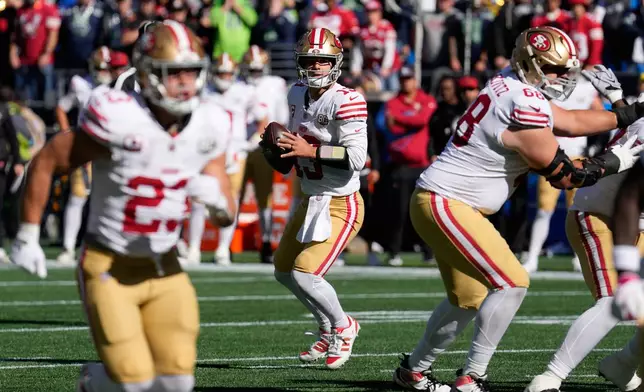 San Francisco 49ers quarterback Brock Purdy, center, looks to pass against the Seattle Seahawks during the first half of an NFL football game Sunday, Oct. 11, 2026, in Seattle. (AP Photo/Stephen Brashear)