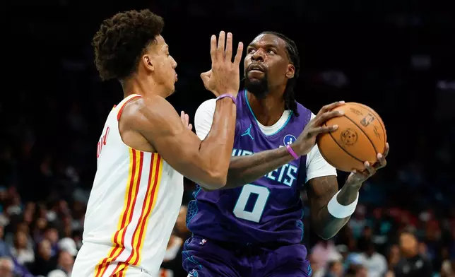 Charlotte Hornets center Naz Reid (0) looks to shoot against Atlanta Hawks forward Jalen Johnson, left, during the first half of an NBA basketball game in Charlotte, N.C., Friday, Oct. 23, 2026. (AP Photo/Nell Redmond)