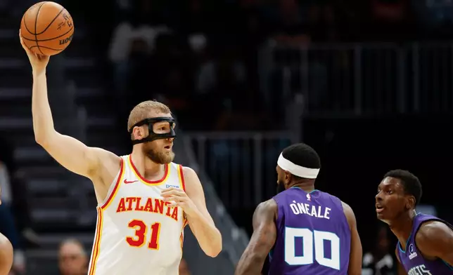 Atlanta Hawks center Jock Landale (31) looks to pass the ball over Charlotte Hornets forwards Royce O'Neale (00) and Moussa Diabate during the first half of an NBA basketball game in Charlotte, N.C., Friday, Oct. 23, 2026. (AP Photo/Nell Redmond)