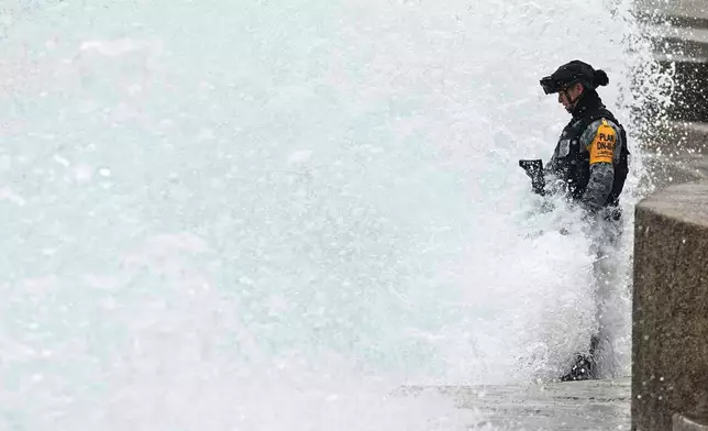 A National Guard stands in the spray as a wave hits the seawall brought by the approaching Hurricane Simon in Puerto Vallarta, Mexico, Sunday, Oct. 11, 2026. (AP Photo/Fernando Llano)