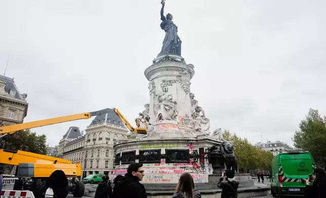People watch and take photos of cleanup efforts after weekend protests over the cost of living turned into rioting and looting across France, in Paris, Wednesday, Oct. 21, 2026. (AP Photo/Teresa Suarez)