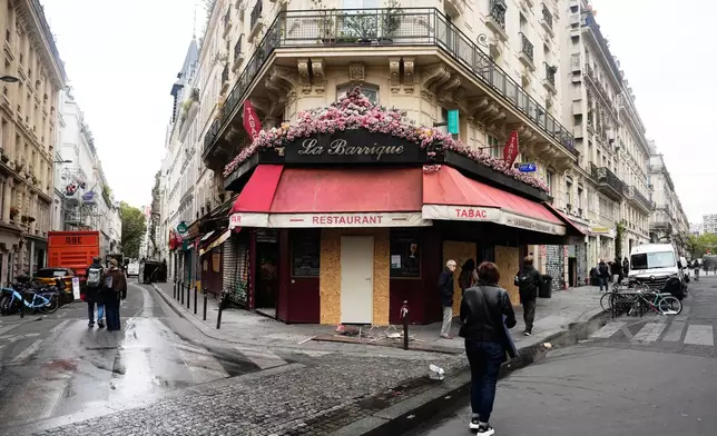 People walk past La Barrique bistrot damaged after the weekend protests over the cost of living turned into rioting and looting across France, in Paris, Wednesday, Oct. 21, 2026. (AP Photo/Teresa Suarez)