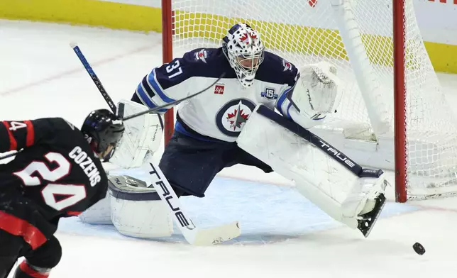 FILE - Winnipeg Jets goaltender Connor Hellebuyck (37) makes a save on a shot by Ottawa Senators' Dylan Cozens (24) during the second period of an NHL hockey game in Ottawa, Ontario, on Saturday, Jan. 3, 2026. (Patrick Doyle/The Canadian Press via AP, File)