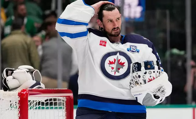 FILE - Winnipeg Jets goaltender Connor Hellebuyck stands by the net during a time out from play against the Dallas Stars in the first period of an NHL hockey game, April 2, 2026, in Dallas. (AP Photo/Tony Gutierrez, File)