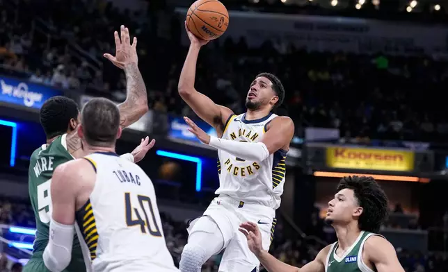 Indiana Pacers guard Tyrese Haliburton, second from right, goes up to shoot over Milwaukee Bucks center Kel'el Ware (9) during the first half of a preseason NBA basketball game in Indianapolis, Friday, Oct. 16, 2026. (AP Photo/Michael Conroy)