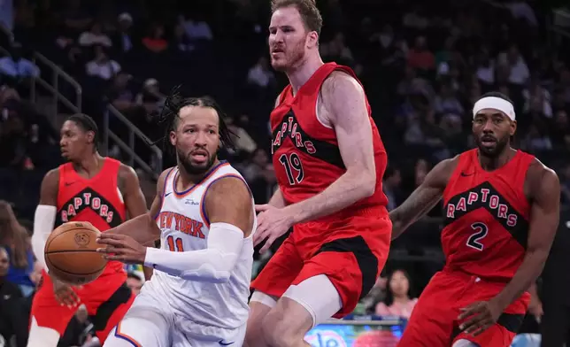 New York Knicks' Jalen Brunson (11) looks to pass away from Toronto Raptors' Jakob Poeltl (19) during the second half of a preseason NBA basketball game Thursday, Oct. 15, 2026, in New York. (AP Photo/Frank Franklin II)
