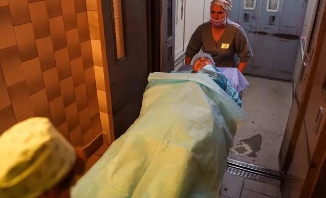 Nurses transport wounded soldier Mykola Kasiuk, into a surgical unit at a hospital in Kyiv, Ukraine, Monday, Sept. 28, 2026. (AP Photo/Evgeniy Maloletka)