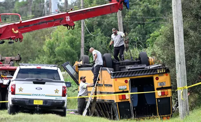 A vehicle recovery crew work to right an overturned school bus after a fatal collision, Monday, Oct. 5, 2026, in Winter Haven, Fla. (AP Photo/Phelan M. Ebenhack)