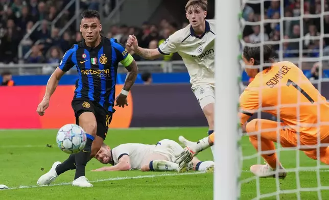 Inter Milan's Lautaro Martinez, left, scores his side's opening goal during the Champions League opening phase soccer match between Inter Milan and Club Brugge in Milan, Italy, Tuesday, Oct. 13, 2026. (AP Photo/Luca Bruno)