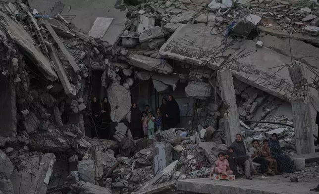 Palestinian women and children watch the Palestine Strongman Championship from among the rubble of destroyed buildings in Gaza City, Friday, Oct. 16, 2026. (AP Photo/Jehad Alshrafi)