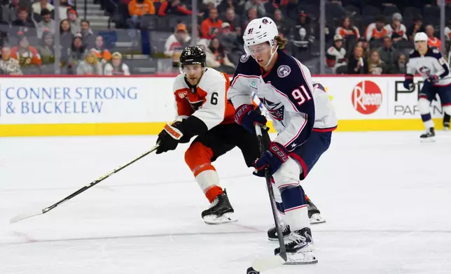 Columbus Blue Jackets' Kent Johnson (91) skates the puck past Philadelphia Flyers' Travis Sanheim during the third period of an NHL hockey game, Tuesday, Oct. 27, 2026, in Philadelphia. (AP Photo/Derik Hamilton)