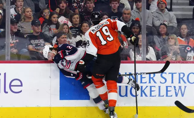 Philadelphia Flyers' Hunter McDonald (19) checks Columbus Blue Jackets' Jake Christiansen during the second period of an NHL hockey game, Tuesday, Oct. 27, 2026, in Philadelphia. (AP Photo/Derik Hamilton)