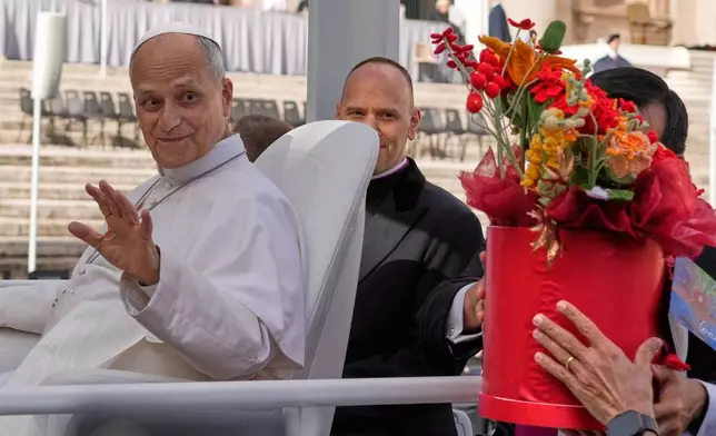 Pope Leo XIV is presented with flowers as he leaves at the end of the general audience in St. Peter's Square at The Vatican, Wednesday, Oct. 21, 2026. (AP Photo/Gregorio Borgia)