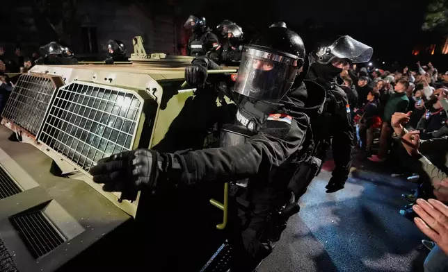 Celebrating people taunt riot police units withdrawing from downtown, after Aleksandar Vucic, leader of the right-wing Serbian Progressive Party (SNS) conceded defeat in the parliamentary election in Belgrade, Serbia, Sunday, Oct. 25, 2026. (AP Photo/Darko Vojinovic)