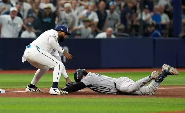 Tampa Bay Rays third baseman Junior Caminero, left, tags out New York Yankees' Austin Wells as Wells tries to stretch his double into a triple during the eighth inning of Game 1 of an American League Division Series baseball game Saturday, Oct. 3, 2026, in St. Petersburg, Fla. (AP Photo/Chris O'Meara)