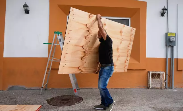 A worker removes wood placed protectively on a pharmacy after the passing of Hurricane Simon in Puerto Vallarta, Mexico, Monday, Oct. 12, 2026. (AP Photo/Fernando Llano)
