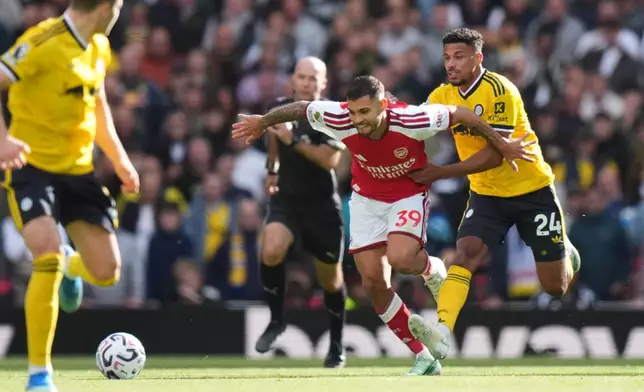 Arsenal's Bruno Guimaraes, centre, challenges for the ball with Leeds' James Justin, right, during the English Premier League soccer match between Arsenal and Leeds United in London, Saturday, Oct. 10, 2026. (AP Photo/Alastair Grant)