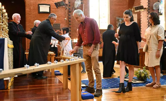 People line up to light a candle during a vigil for independent federal member of parliament, Helen Haines at the Holy Trinity Anglican Cathedral in Wangaratta, Australia, Tuesday, Oct. 20, 2026. (James Ross/AAP Image via AP)