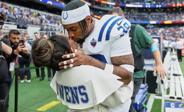Simone Biles, multiple Olympic and World champion gymnast, kisses her husband Indianapolis Colts safety Jonathan Owens (38) on the side of the field before an NFL football game between Indianapolis Colts and Washington Commanders in London, Sunday, Oct. 4, 2026. (AP Photo/Ian Walton)