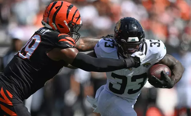 Cincinnati Bengals defensive end Myles Murphy (99) gets a face mask penalty against Jacksonville Jaguars running back Bhayshul Tuten (33) during an NFL football game in Cincinnati, Sunday, Oct. 4, 2026. (AP Photo/Tanner Pearson)