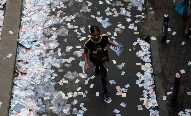 A voter walks toward a polling station through a street carpeted with campaign leaflets during general elections in Rio de Janeiro, Brazil, Sunday, Oct. 4, 2026. (AP Photo/Bruna Prado)