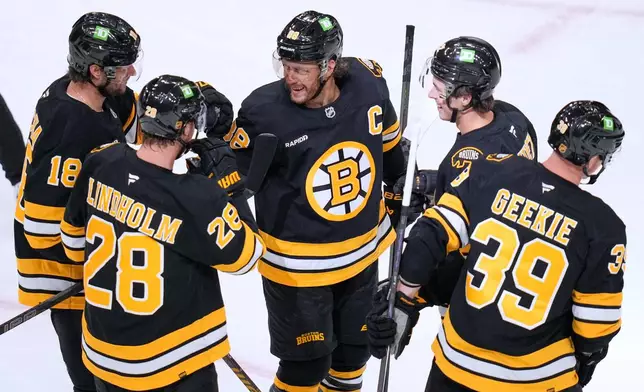 Boston Bruins' David Pastrnak, center, celebrates with teammates after a goal by Morgan Geekie (39) during the second period of an NHL hockey game, Thursday, Oct. 8, 2026, in Boston. (AP Photo/Charles Krupa)