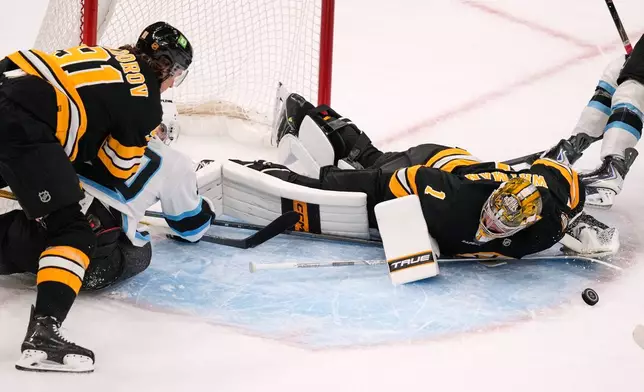Boston Bruins' Jeremy Swayman (1) drops to the ice for a save against a shot by Utah Mammoth's Daniil But, second from left, who is held to the ice by Nikita Zadorov (91) during the first period of an NHL hockey game, Thursday, Oct. 8, 2026, in Boston. (AP Photo/Charles Krupa)