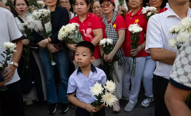 People watch as 731 sets of martyrs' remains found at Le Thi Rieng Cultural Park are transferred for burial at Ho Chi Minh City Martyrs' Cemetery Wednesday, Oct. 14, 2026, in Ho Chi Minh City, Vietnam. (AP Photo/Thanh Hue)