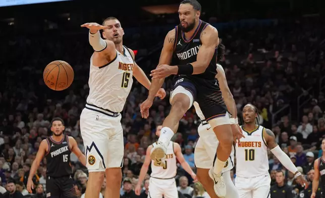 Phoenix Suns forward Dillon Brooks, front right, passes the ball around Denver Nuggets center Nikola Jokic (15) during the first half of an NBA Cup basketball game, Friday, Oct 30, 2026, in Phoenix. (AP Photo/Rick Scuteri)
