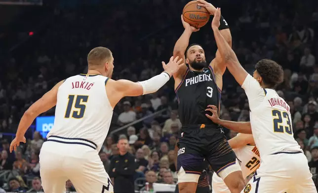 Phoenix Suns forward Dillon Brooks (3) looks to shoot over Denver Nuggets center Nikola Jokic (15) and forward Cameron Johnson (23) during the first half of an NBA Cup basketball game, Friday, Oct 30, 2026, in Phoenix. (AP Photo/Rick Scuteri)