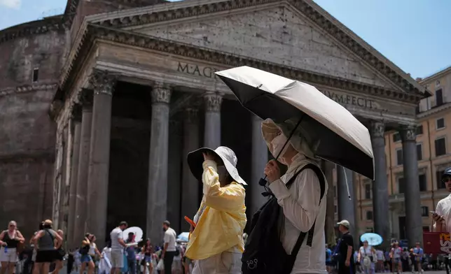 FILE - Tourists use umbrellas to take shelter from the sun in Pantheon Square in Rome, June 29, 2026. (AP Photo/Alessandra Tarantino, File)
