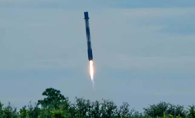 The booster from a SpaceX Falcon 9 rocket returns to pad 40 after launching the crew capsule at the Cape Canaveral Space Force Station in Cape Canaveral, Fla., Thursday, Oct. 1, 2026. (AP Photo/John Raoux)