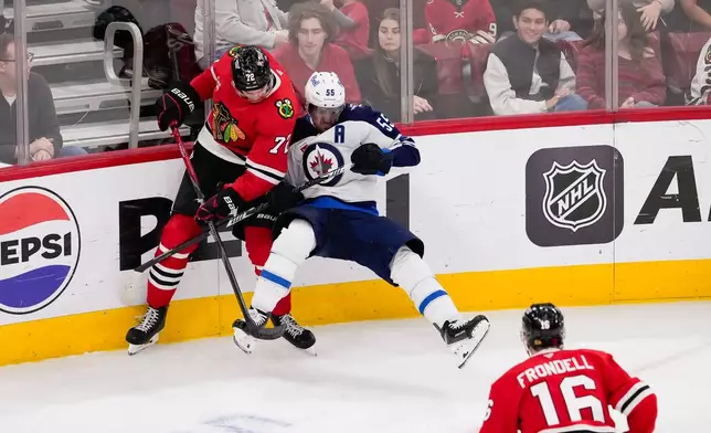 Chicago Blackhawks defenseman Alex Vlasic, left, upends Winnipeg Jets center Mark Scheifele, right, during the second period of an NHL hockey game, Thursday, Oct. 15, 2026, in Chicago. (AP Photo/Harry Figiel)