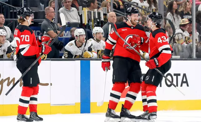 New Jersey Devils defenseman Luke Hughes (43) is congratulated by right wing Anthony Mantha (39) and center Jesper Boqvist (70) after scoring against the Vegas Golden Knights during the first period of an NHL hockey game Friday, Oct. 30, 2026, in Las Vegas. (Steve Marcus/Las Vegas Sun via AP)