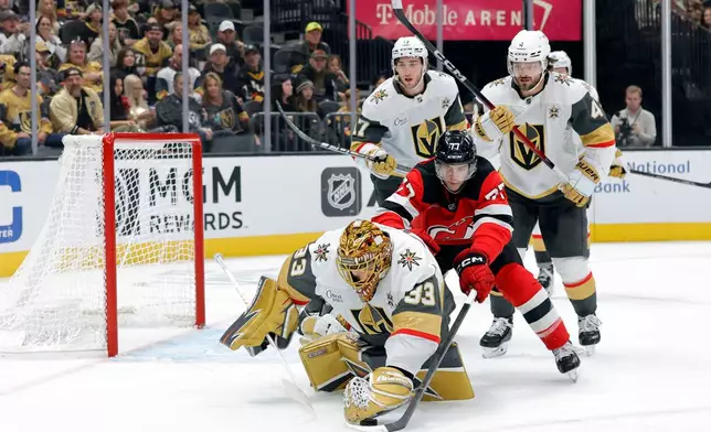 Vegas Golden Knights goaltender Adin Hill (33) covers the puck in front pf New Jersey Devils right wing Luke Evangelista (77) during the second period of an NHL hockey game Friday, Oct. 30, 2026, in Las Vegas. (Steve Marcus/Las Vegas Sun via AP)