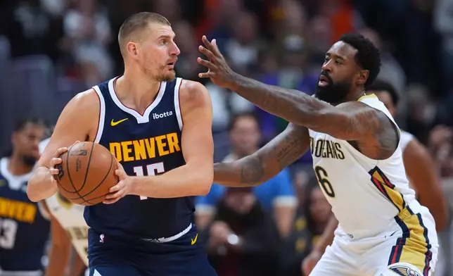 Denver Nuggets center Nikola Jokić, left, looks to pass the ball as New Orleans Pelicans center DeAndre Jordan, right, defends in the first half of an NBA basketball game Saturday, Oct. 24, 2026, in Denver. (AP Photo/David Zalubowski)
