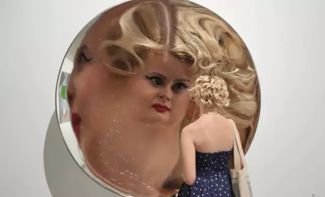 A visitor is looking in a mirror, the Inverse Reverse Perverse installation by Cerith Wyn Evans, which is displayed during a media preview of "The 90s: Art and Fashion exhibition" at Tate Britain in London, Tuesday, Oct. 6, 2026. (AP Photo/Kin Cheung)