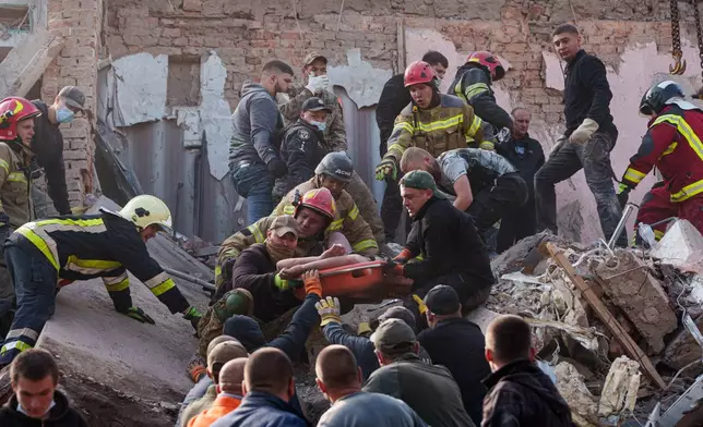 Locals and rescuers carry out an injured man from a residential building destroyed in a Russian missile strike on Pryluky, Ukraine, Wednesday, Oct. 7, 2026. (AP Photo/Evgeniy Maloletka)