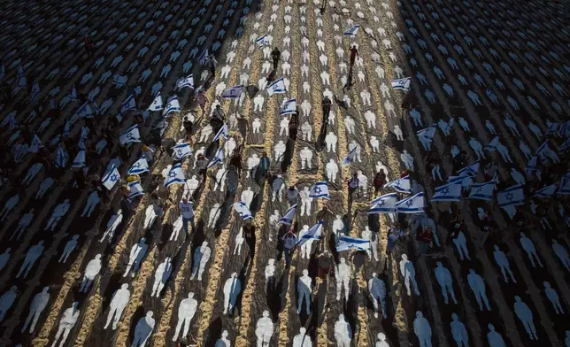 People carrying Israeli flags walk through an installation marking the third anniversary of the Oct. 7, 2023, Hamas attack on Israel, on the beachfront in Tel Aviv, Israel, Wednesday, Oct. 7, 2026. (AP Photo/Oded Balilty)